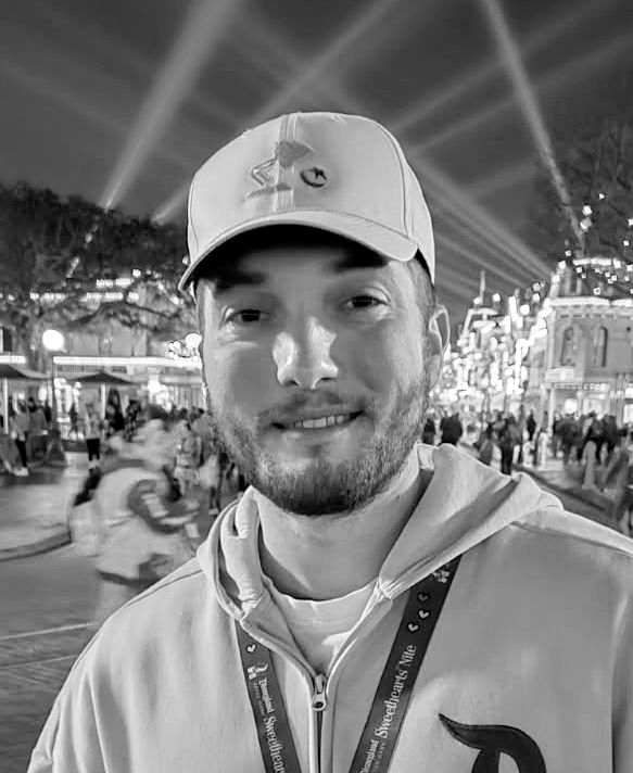 Taylor Erickson smiling in front of a brightly lit amusement park backdrop.